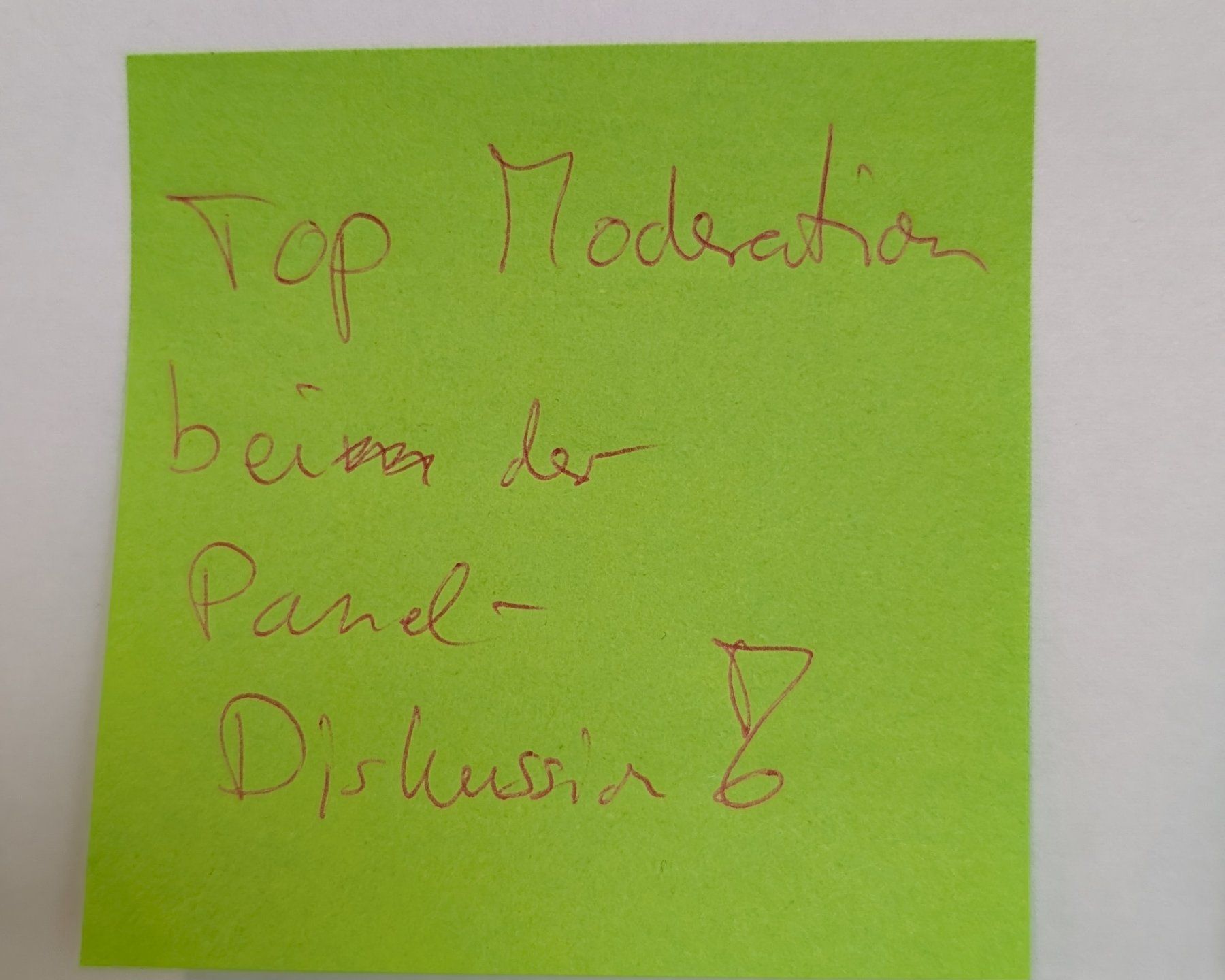 Grünes Post-it an der Feedbackwand mit der handschriftlichen Notiz „Top Moderation bei der Panel-Diskussion“.