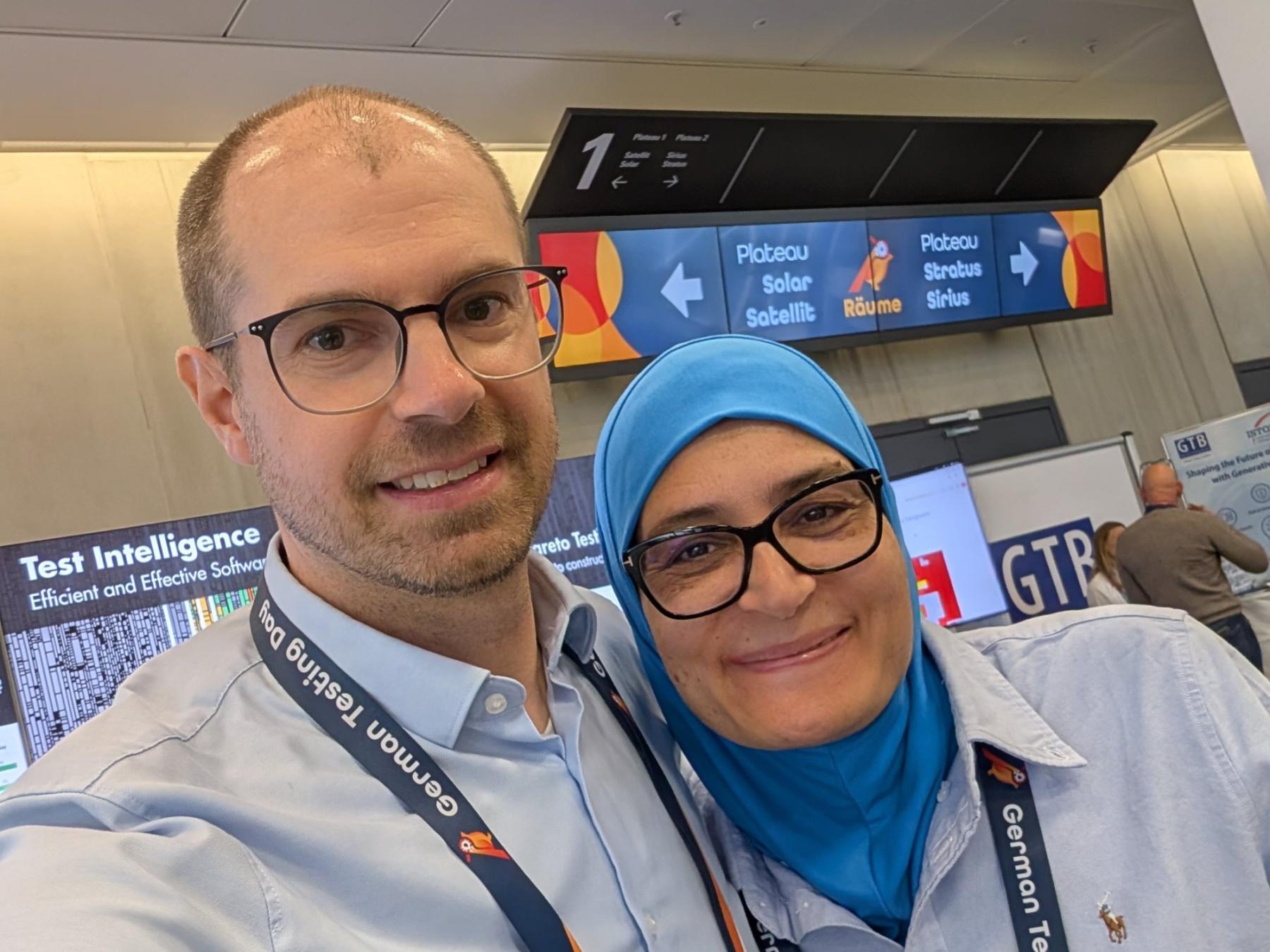 Selfie von Matthias Groß und Lilia Gargouri vor der Raumbeschilderung des German Testing Day 2026.